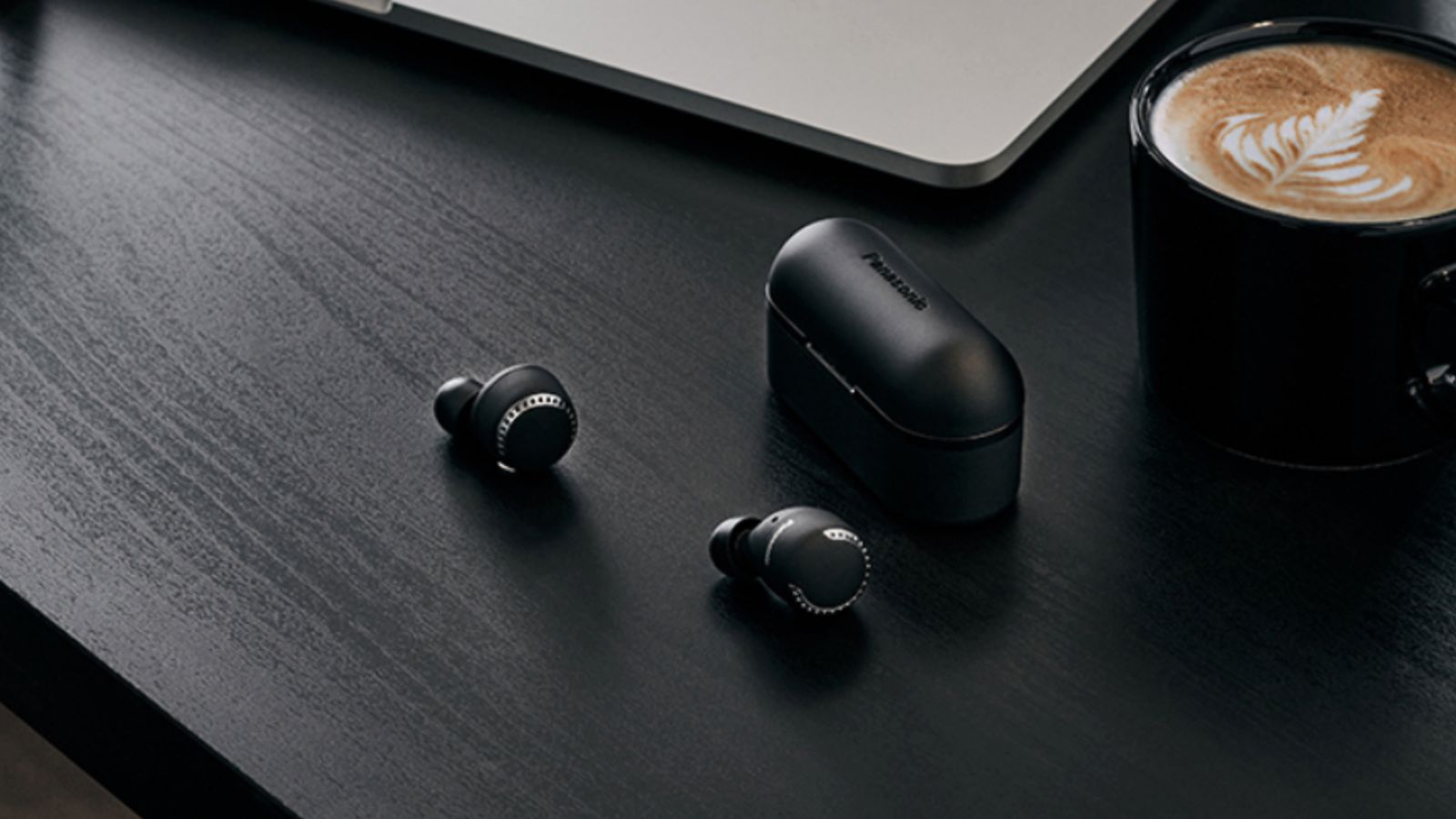 Best Android earbuds - Image of two wireless Panasonic earbuds on a desk next to a wireless charging case.